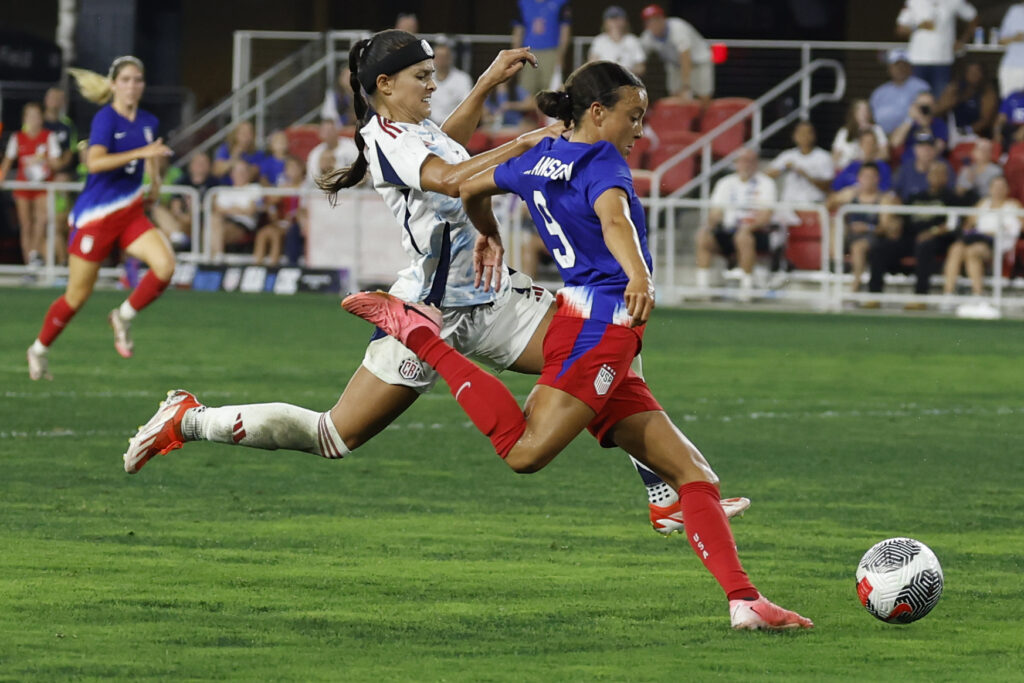 United States forward Mallory Swanson plants her left foot and prepares to shoot the ball with her right foot.