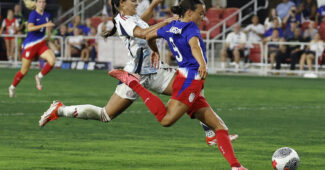 United States forward Mallory Swanson plants her left foot and prepares to shoot the ball with her right foot.