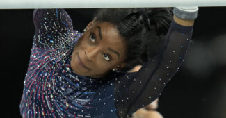 Simone Biles reaches for the bar during Olympic podium training in Paris.