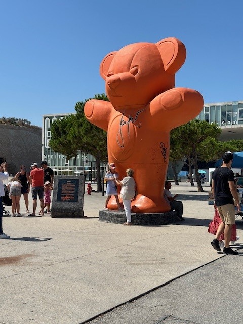 Giant teddy bear statue is pictured with people posing for photos in front of it
