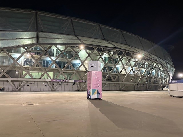 Paris 2024 logo is displayed on a wayfinder in front of the Olympic soccer stadium in Nice
