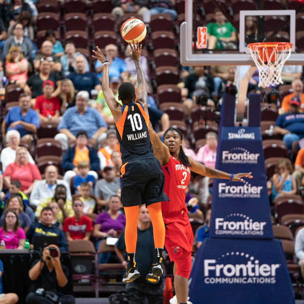 Washington Mystics forward Myisha Hines-Allen extends her right arm to contest a jump shot by Connecticut Sun guard Courtney Williams.