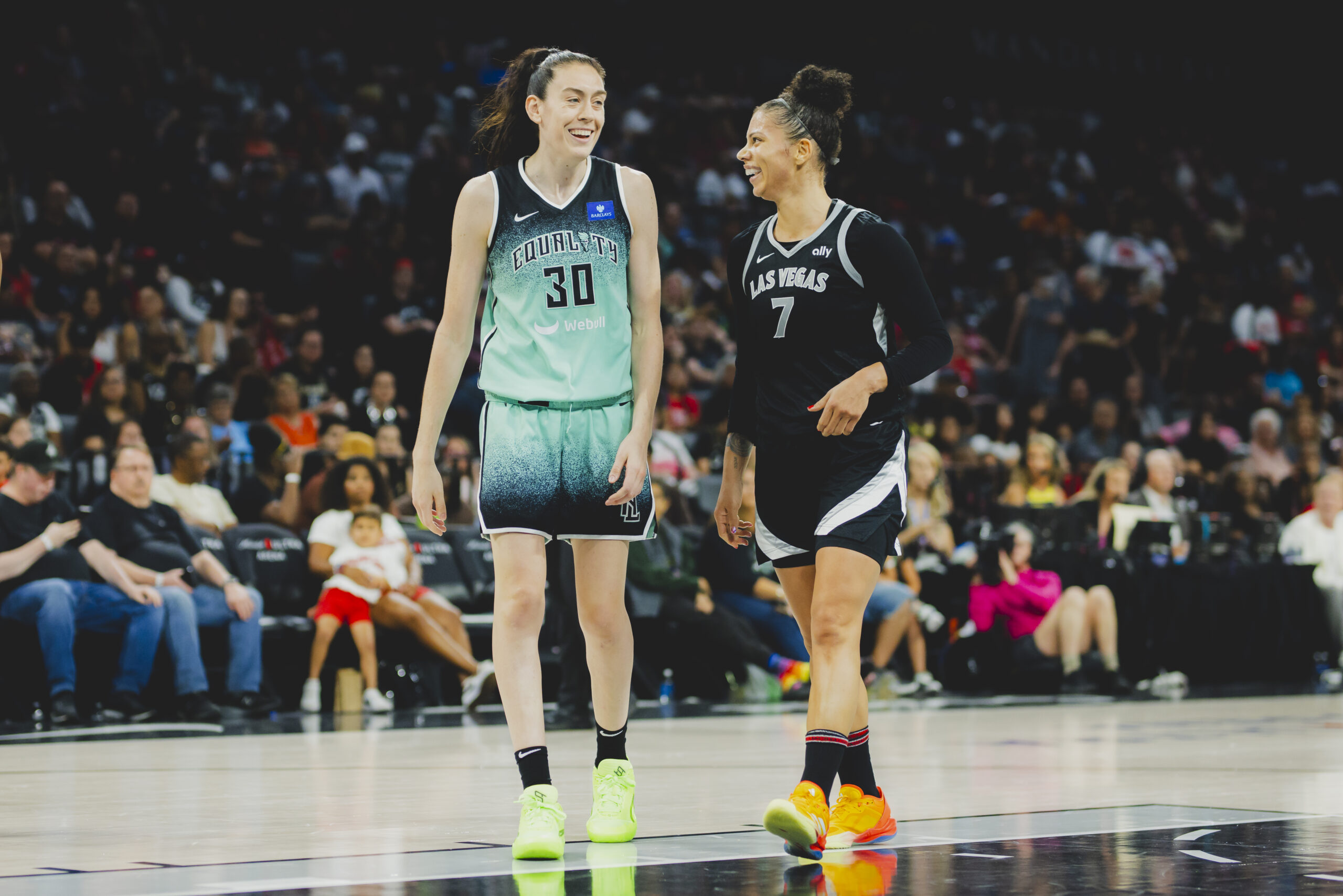 New York Liberty forward Breanna Stewart and Las Vegas Aces forward Alysha Clark smile at each other during a game.