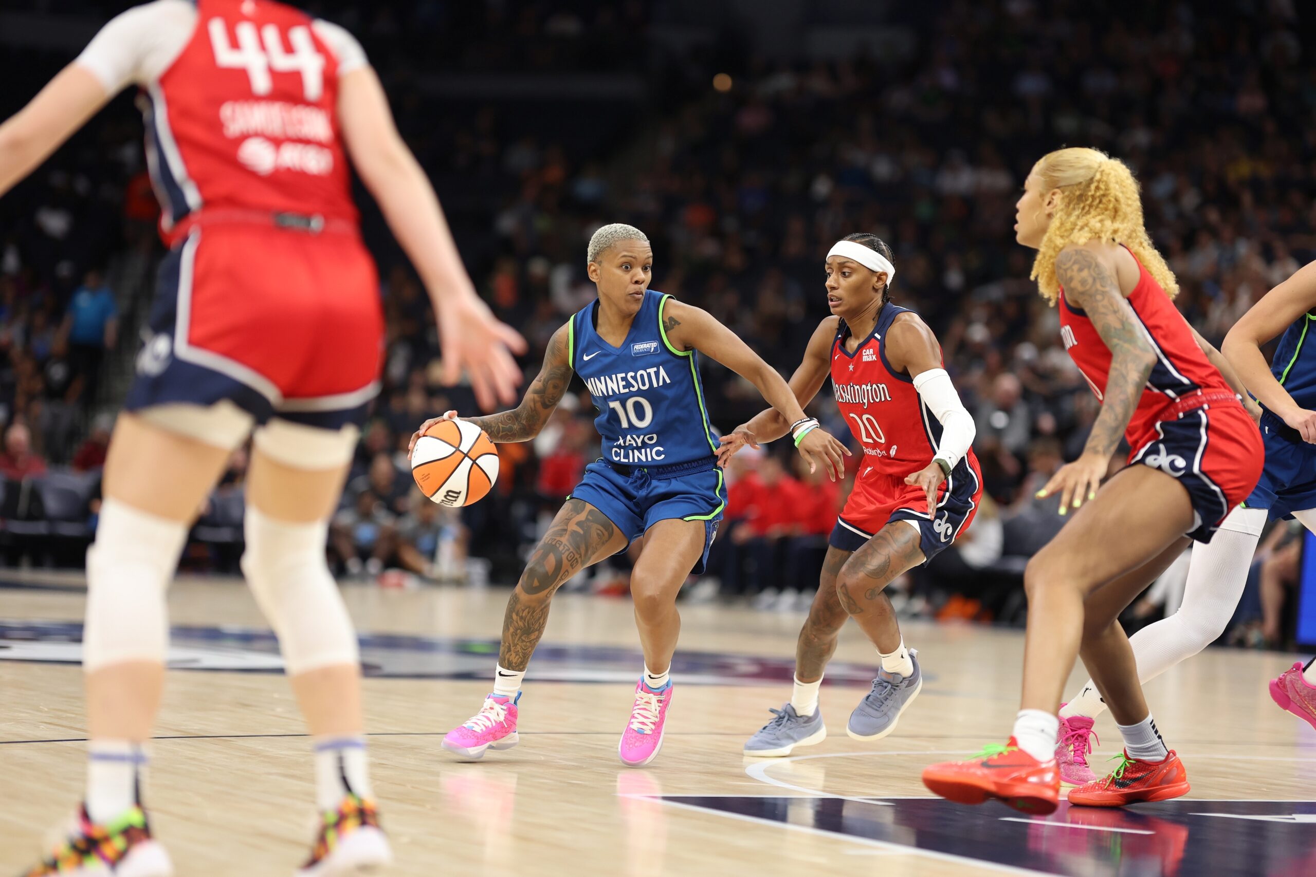 Washington Mystics guard Brittney Sykes defends Minnesota Lynx guard Courtney Williams, who is dribbling the ball. Mystics center/forward Shakira Austin is ready to help in the paint, and guard Karlie Samuelson defends on the wing.