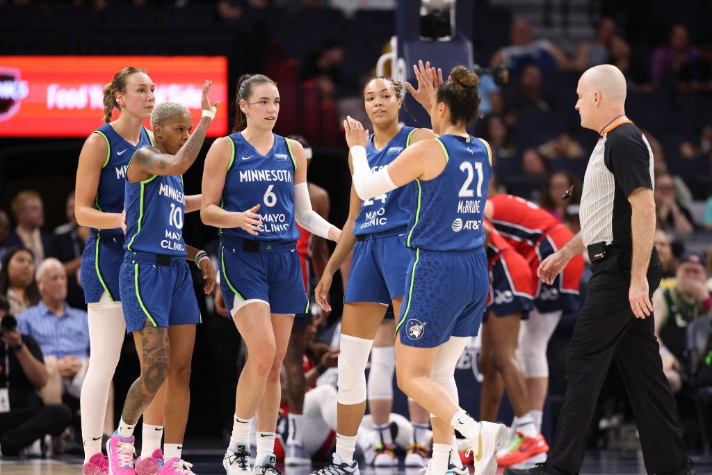 The Minnesota Lynx starting five exchanges high fives as the players gather on the court.