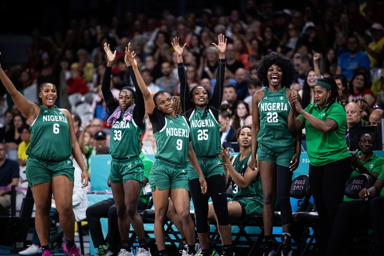 Members of the Nigeria women's basketball team react excitedly on the sideline in their green uniforms