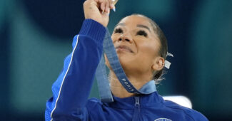 Gymnast Jordan Chiles holding up a bronze medal.