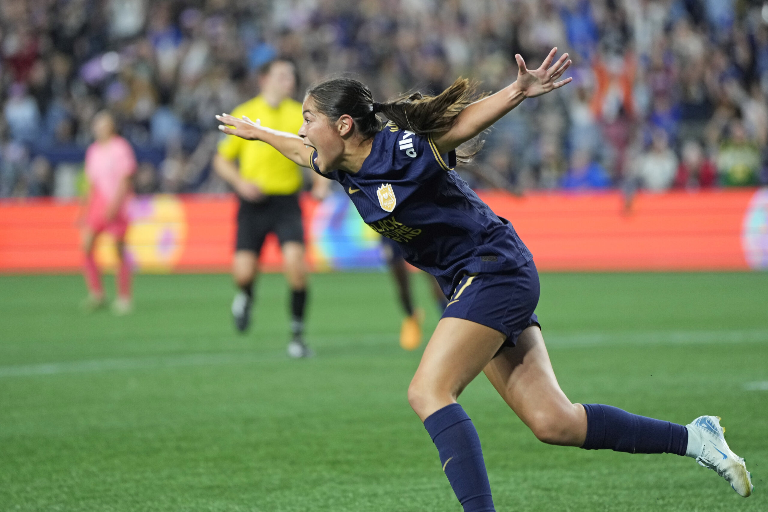 Seattle Reign FC forward Emeri Adames runs with outspread arms to celebrate a goal