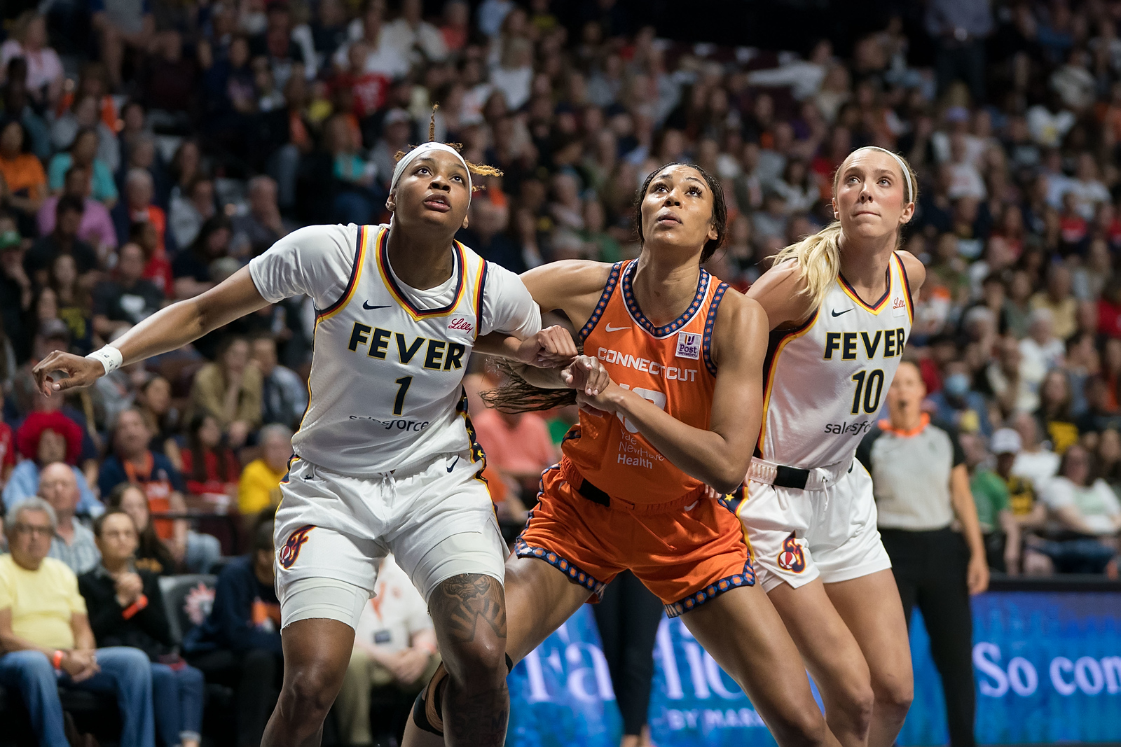 Indiana Fever's NaLyssa Smith and Lexie Hull battle for a rebound against Connecticut's Olivia Nelson-Ododa.