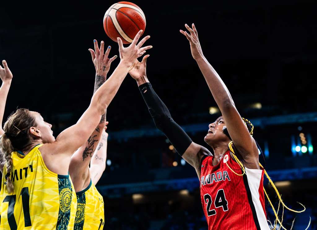 Canada forward Aaliyah Edwards and two Australia players reach their arms up to try to grab a loose ball.