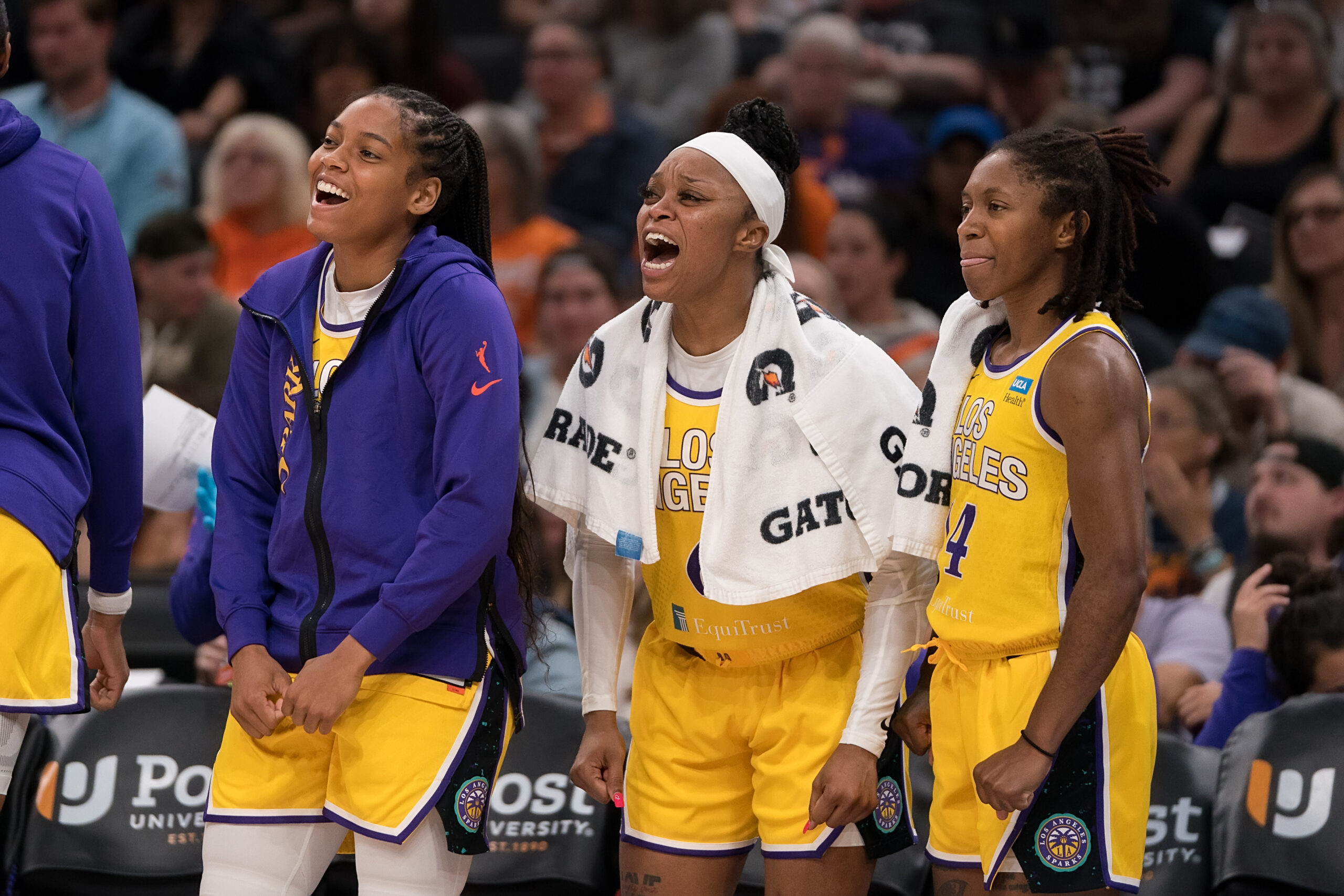 Los Angeles Sparks guards Zia Cooke, Odyssey Sims and Crystal Dangerfield smile and cheer from the bench.