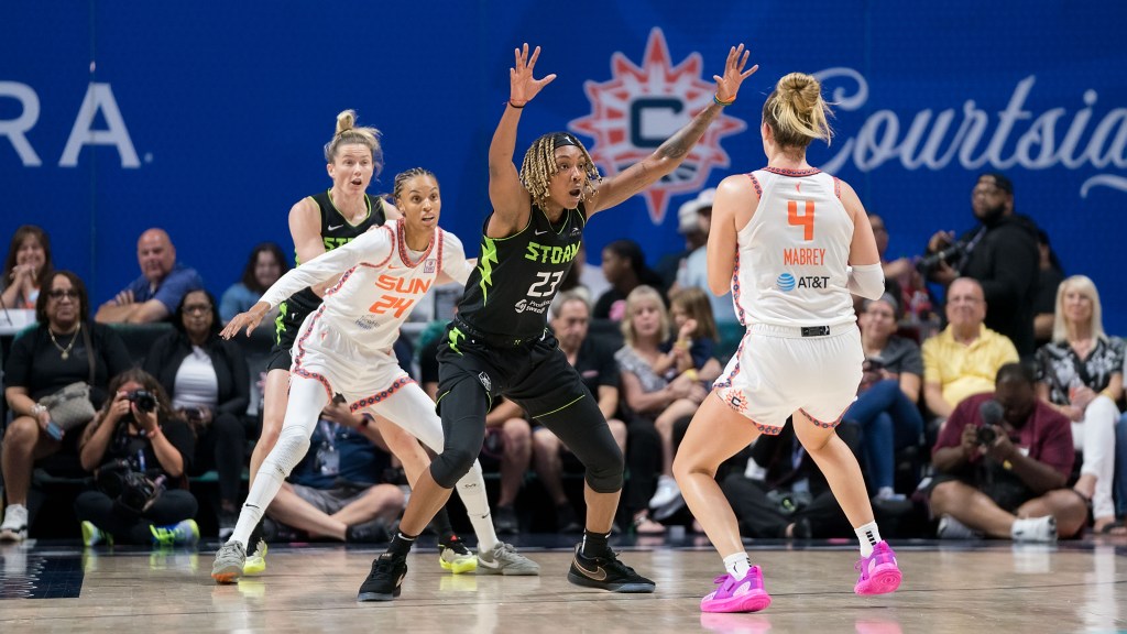Seattle Storm forward Jordan Horston bends her knees and has both hands up to discourage Connecticut Sun guard Marina Mabrey from passing the ball inside the arc to forward/guard DeWanna Bonner.