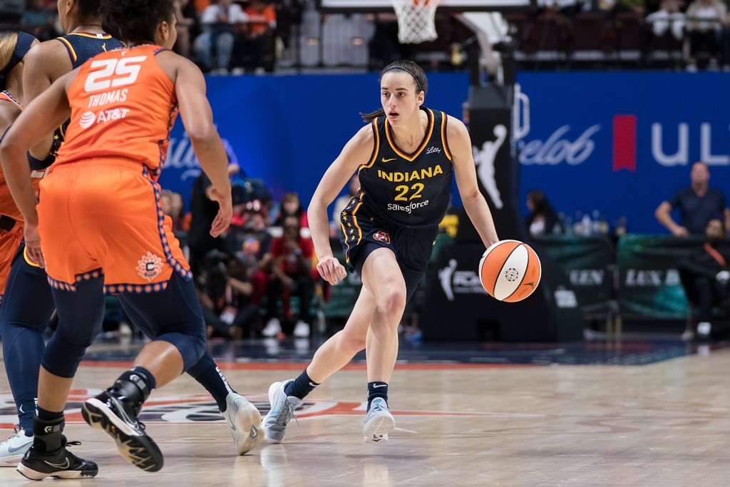 Indiana Fever guard Caitlin Clark handles the ball while a Connecticut Sun opponent approaches