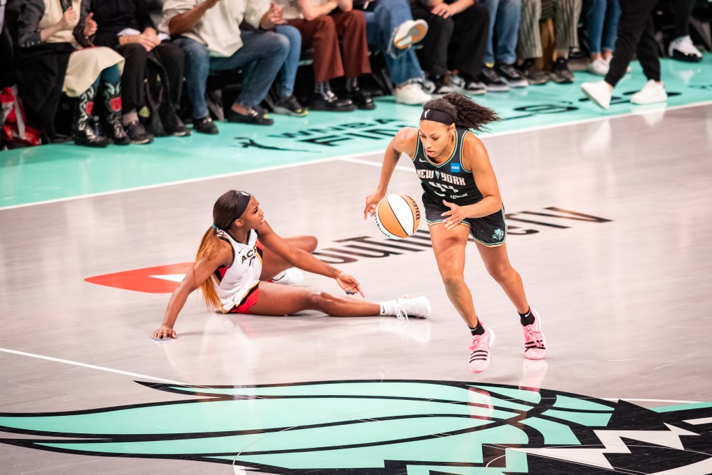 New York Liberty wing Betnijah Laney-Hamilton steals the ball from Las Vegas Aces guard Jackie Young near midcourt and runs across the center-court logo.