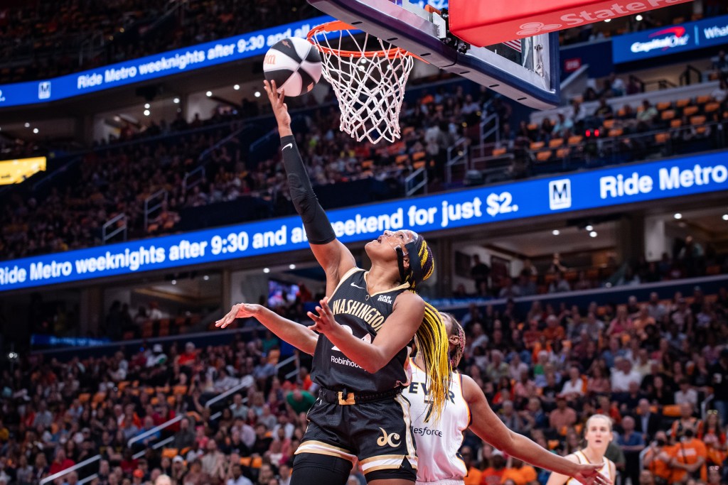 Washington Mystics forward Aaliyah Edwards is underneath the basket. She jumps and looks up at the rim as she attempts a right-handed layup with a defender on her back.