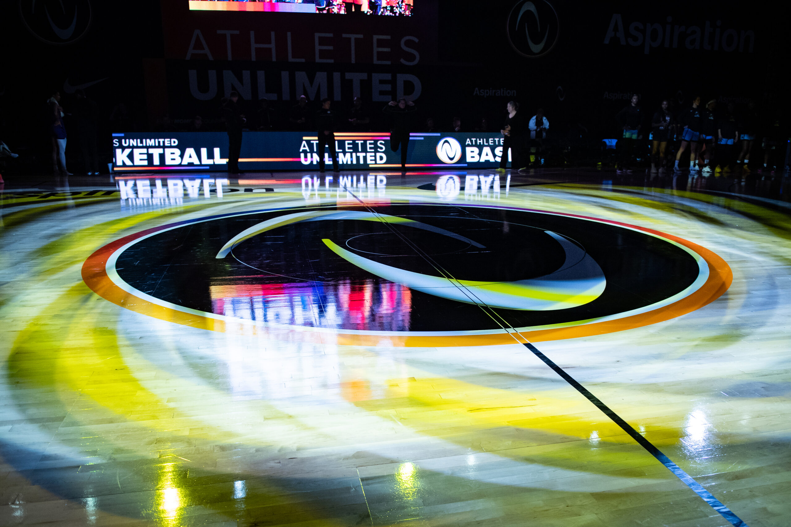 The Athletes Unlimited logo shines on the basketball court before a game.
