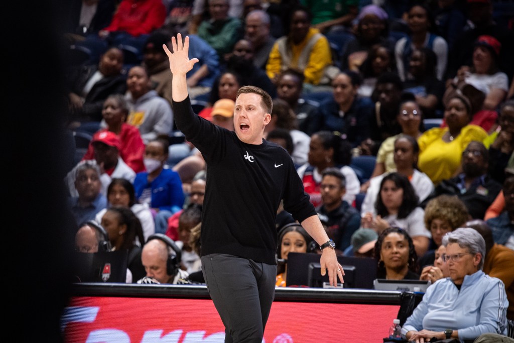 Washington Mystics head coach Eric Thibault walks down the sideline and holds up his right hand, showing his five fingers.
