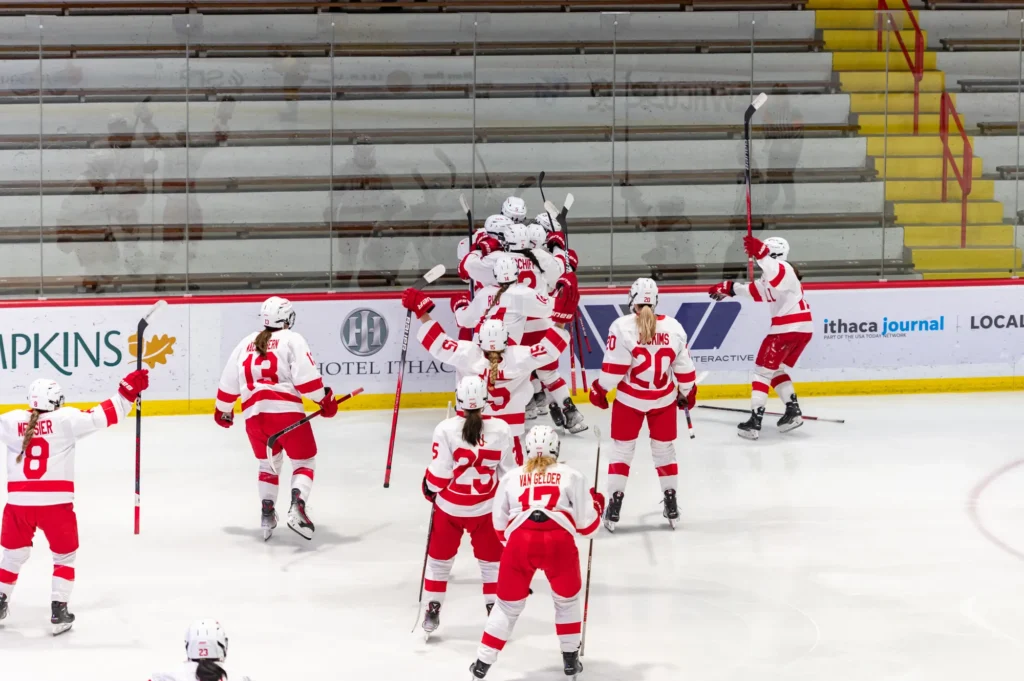 Cornell whole team celebrates along the glass after an overtime winner.