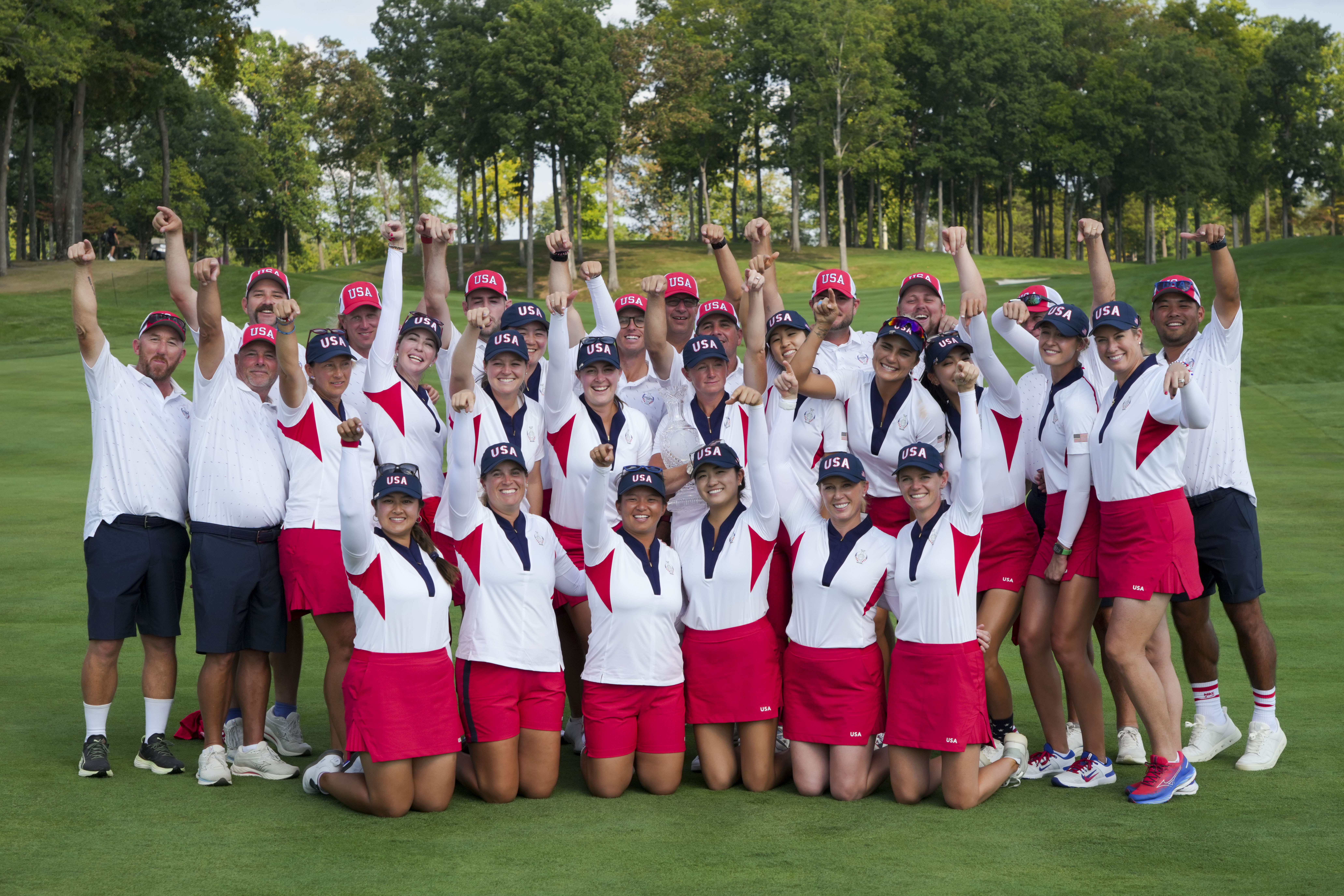 U.S.A. players and caddies pose in a group and raise their arms in victory after winning the Solheim Cup