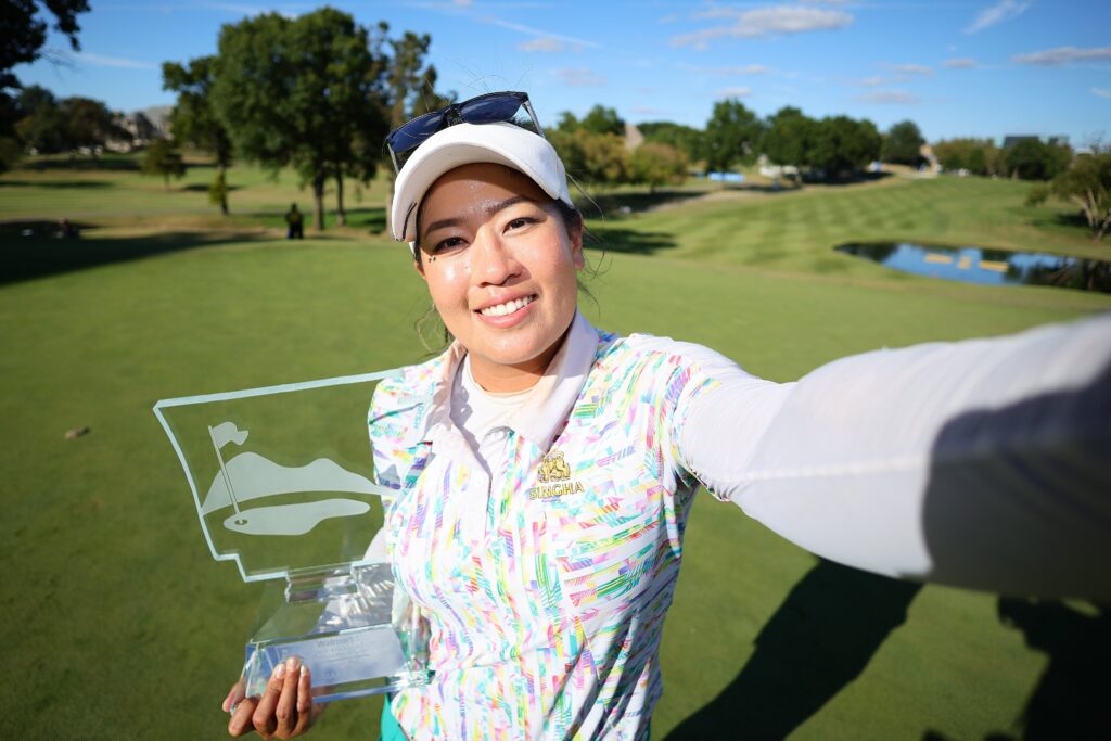 Jasmine Suwannapura takes a selfie, holding the NW Arkansas Championship trophy in her right hand and extending her left arm out to take the photo