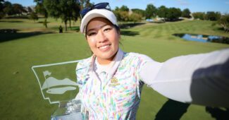 Jasmine Suwannapura takes a selfie, holding the NW Arkansas Championship trophy in her right hand and extending her left arm out to take the photo