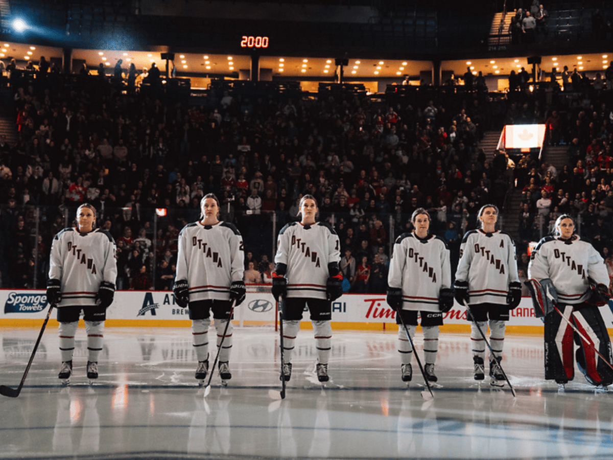 Six Ottawa players stand on the blue line before a game. They are all wearing white away uniforms.