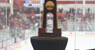 NCAA women's hockey championship trophy is on display with a hockey rink in the background