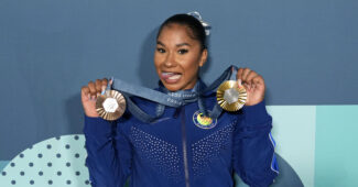 Jordan Chiles in a blue warmup suit with her team gold and individual bronze Olympic medals.