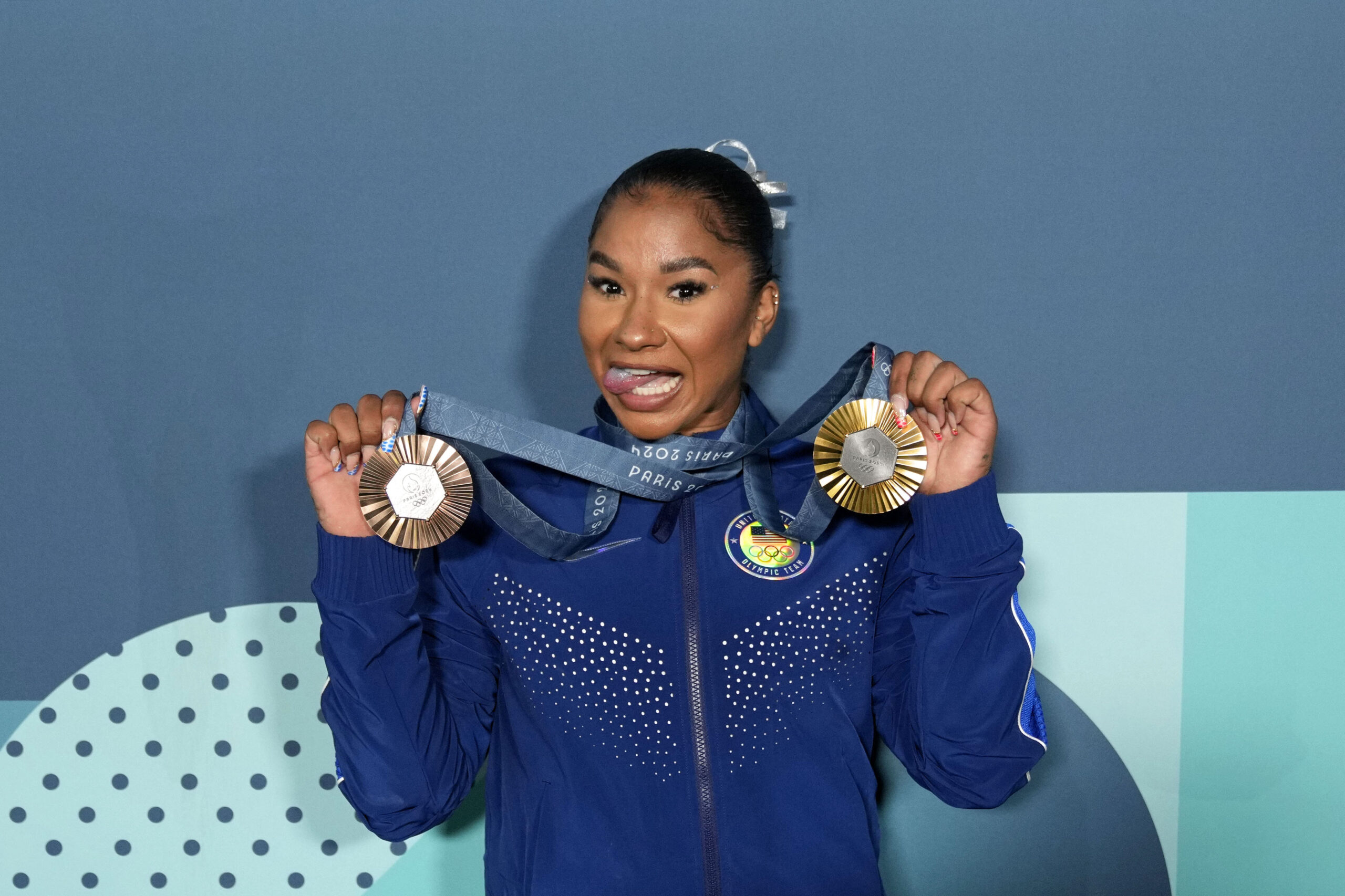 Jordan Chiles in a blue warmup suit with her team gold and individual bronze Olympic medals.
