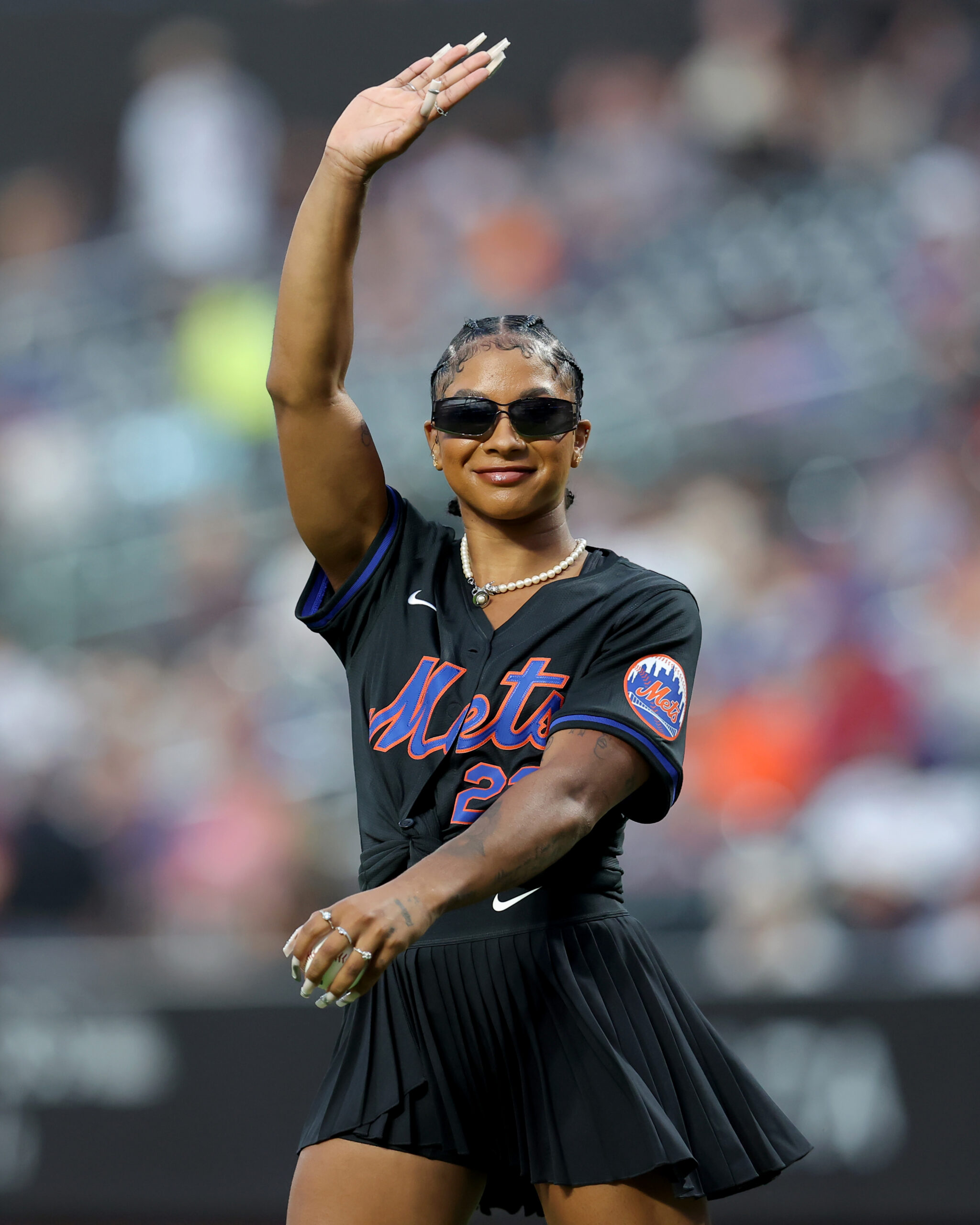 Jordan Chiles, in a black Mets minidress, prepares to throw a pitch.