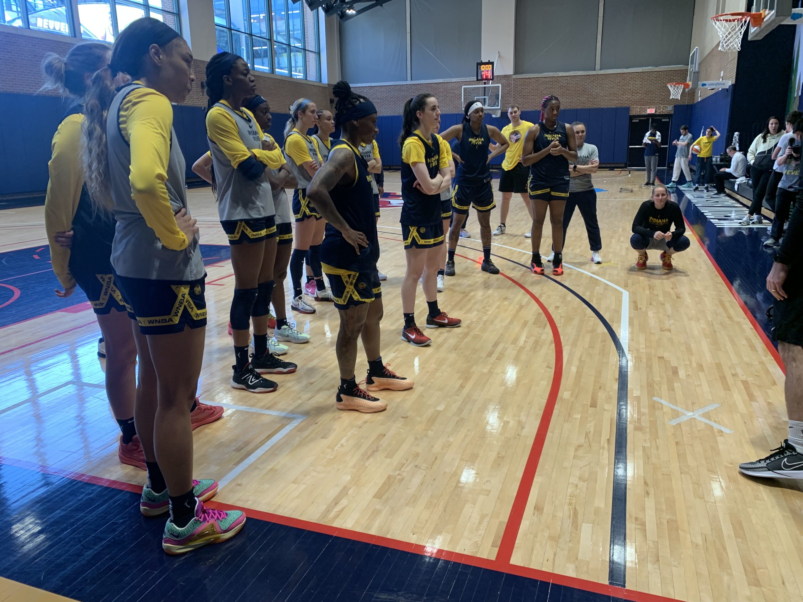 Indiana Fever players stand while receiving coaching instructions during practice