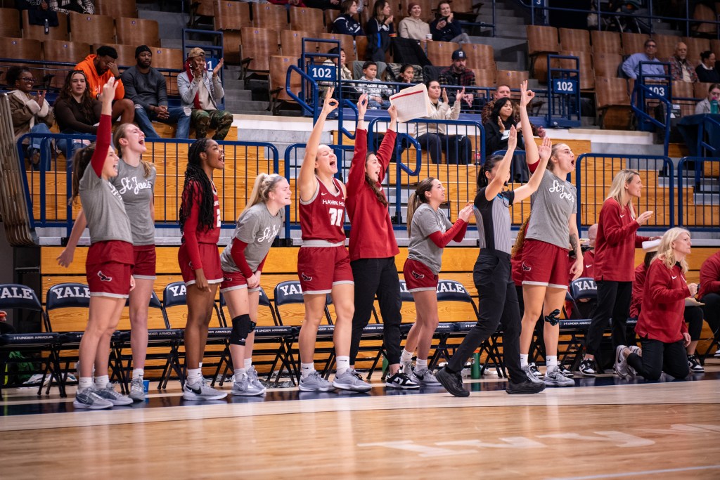 Players on Saint Joseph's bench cheer and raise their hands to celebrate a teammate's made 3-pointer.