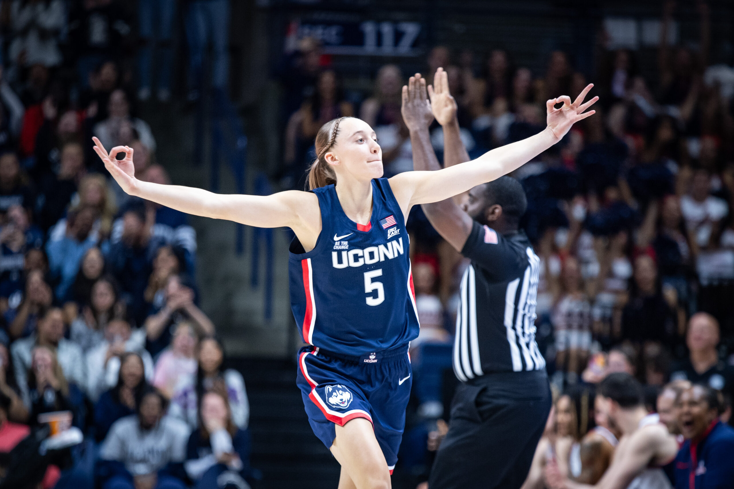 Paige Bueckers motions to the crowd with both hands using the 3-point sign