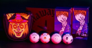 A series of Halloween inspired golf accessories line up across a black background. The items, a putter cover with a witches face and golf balls with spooky icons, seem to glow in the dark.