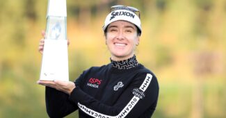Hannah Green smiles and holds up the BMW Ladies Championship trophy to her right.
