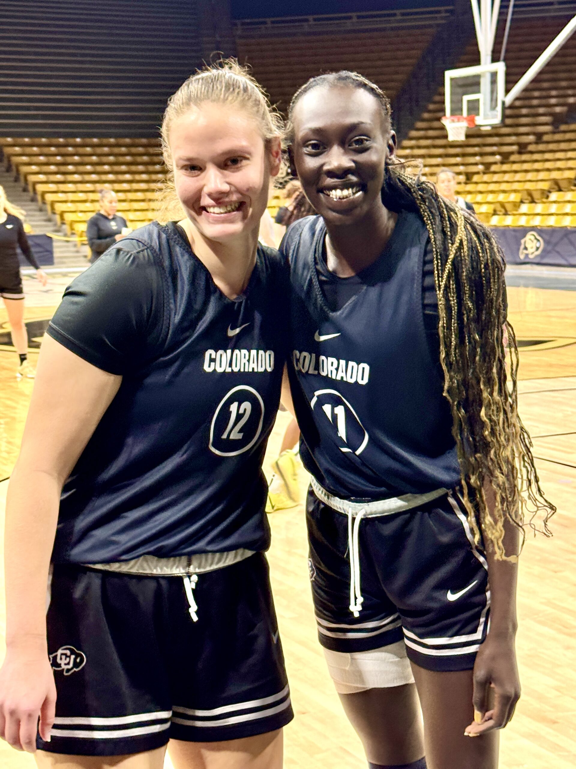 Lior Garzon and Nyamer Diew smile with the arms around each other on the basketball court at the University of Colorado Special Events Center.