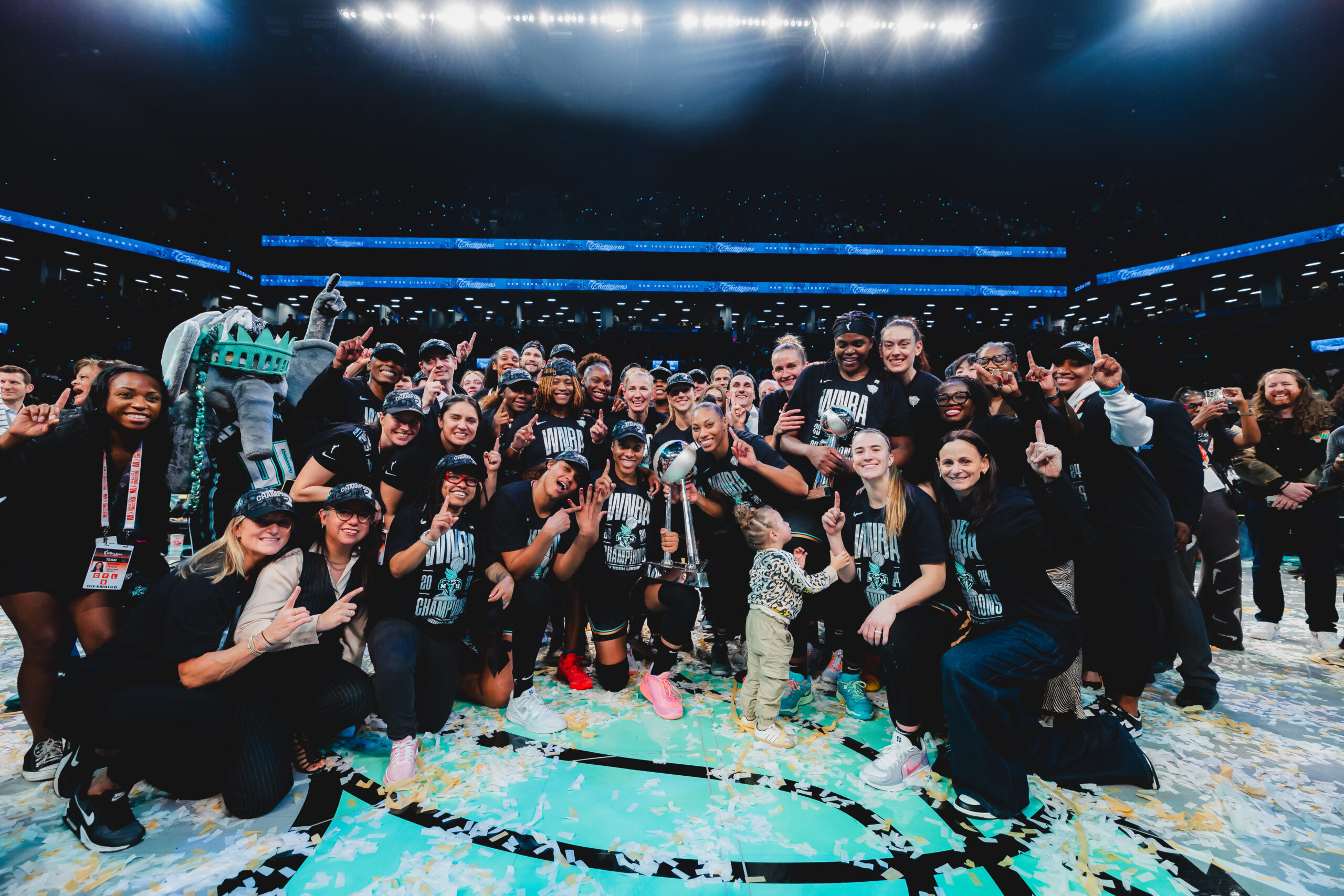 The entire New York Liberty roster, staff and mascot Ellie the Elephant pose with the WNBA championship trophy.