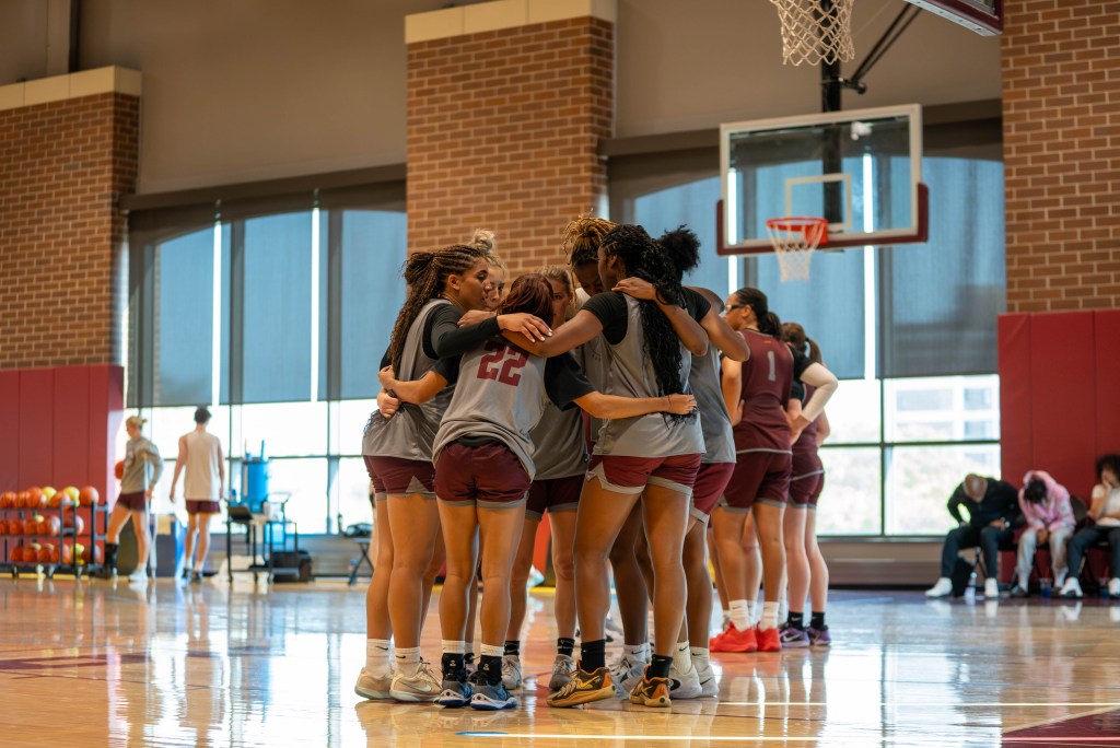 Loyola Chicago players wrap their arms each other in a huddle on the team's practice court.