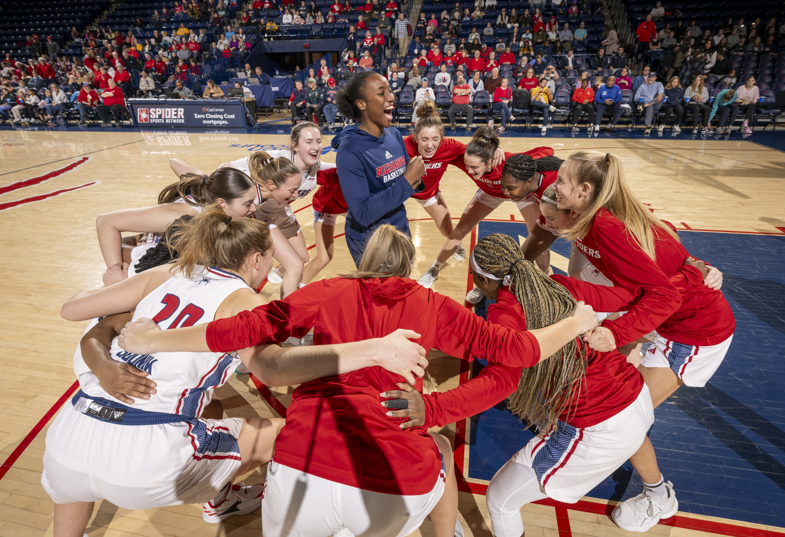 Richmond players lean forward with their arms around each other in a circle around one player.