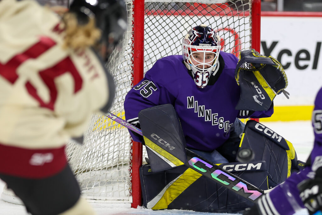 Minnesota goalie Maddie Rooney defends the net while a puck is shot in her direction by an opposing player