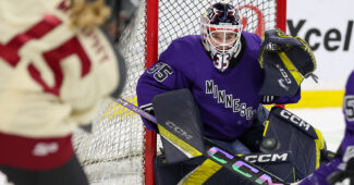 Minnesota goalie Maddie Rooney defends the net while a puck is shot in her direction by an opposing player