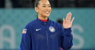Suni Lee waves to the audience during the Olympics