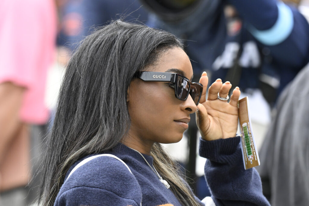 Simone Biles adjusts her sunglasses as she watches an NFL game in Chicago.