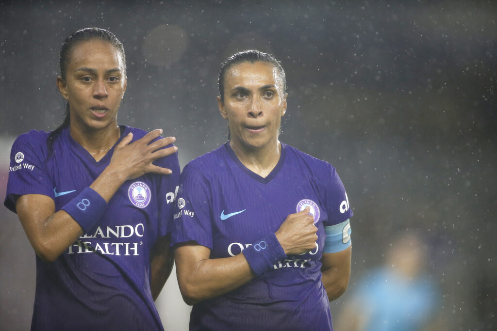 Orlando Pride forwards Adriana Leal da Silva (9) and Marta (10) stand with hands on chests in the rain prior to a match