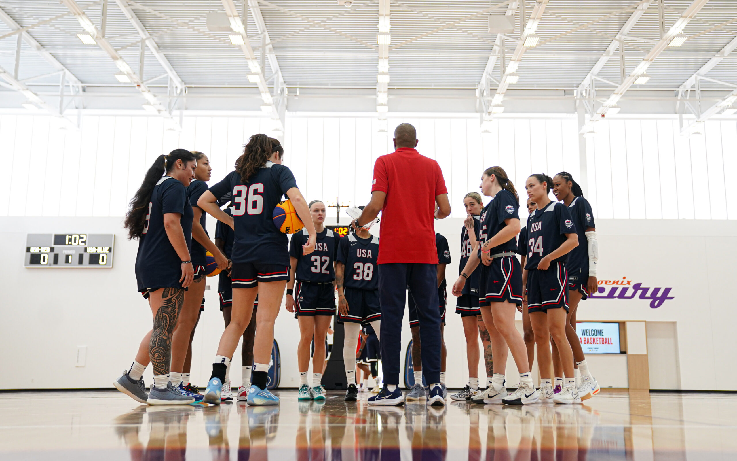 Players stand in a circle listening to a coach