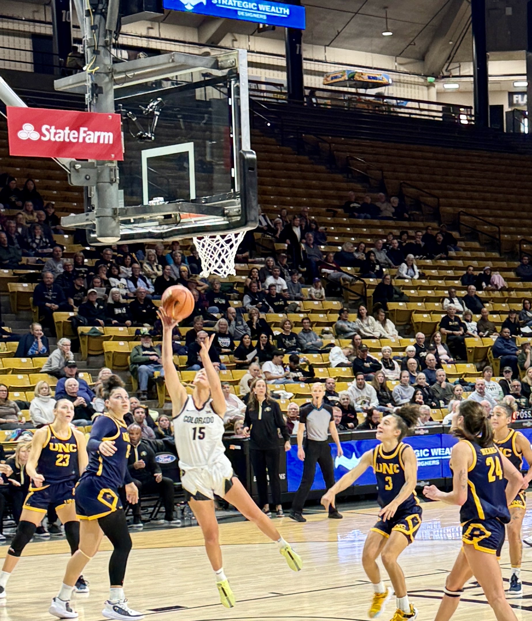 Colorado guard Kindyll Wetta jumps toward the basket as she is surrounded by Northern Colorado defenders in a basketball game.