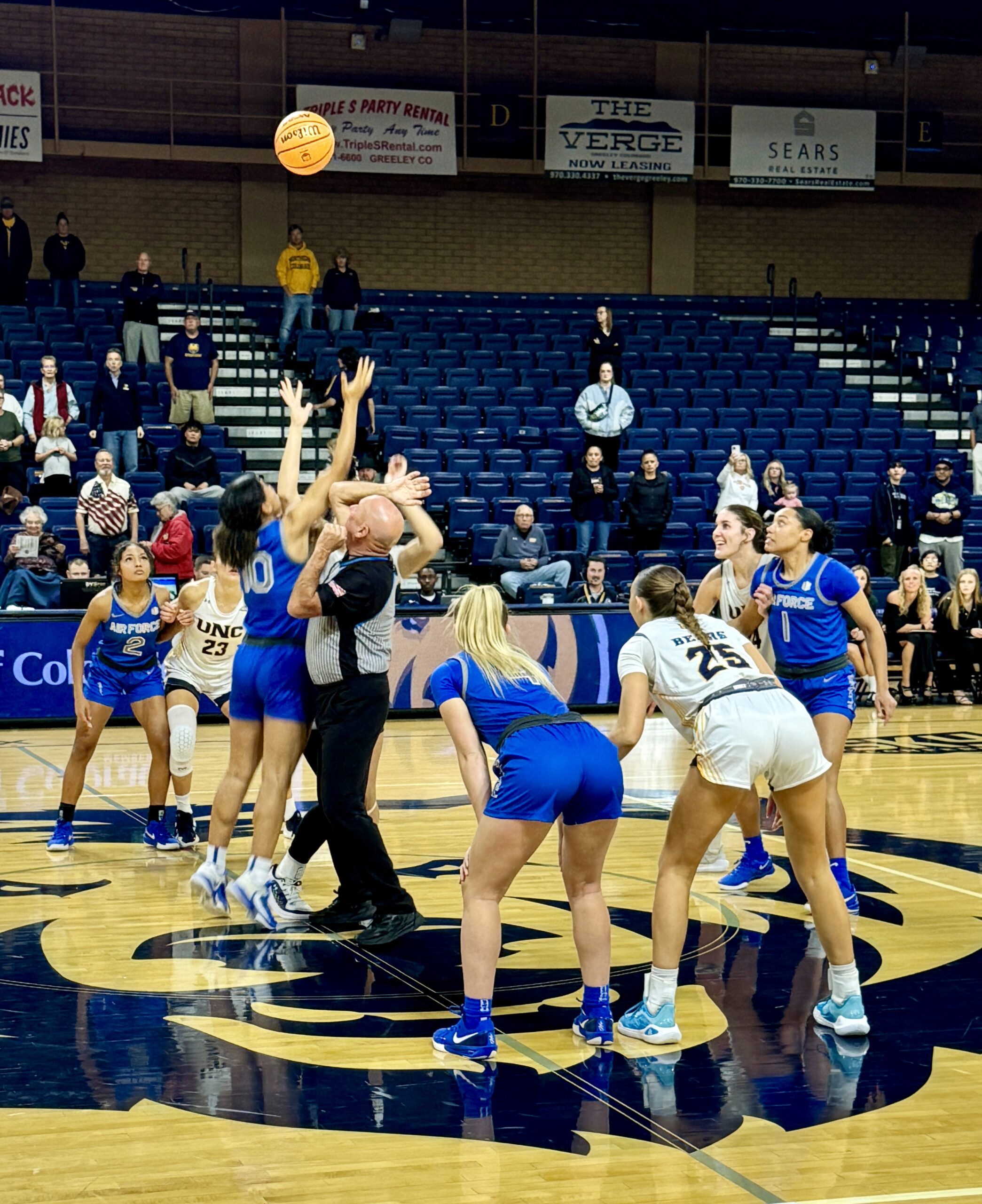 Air Force forward Jayda McNabb and Northern Colorado forward Aniah Hall jump to to control the ball in the opening tip off at center court of a basketball game.