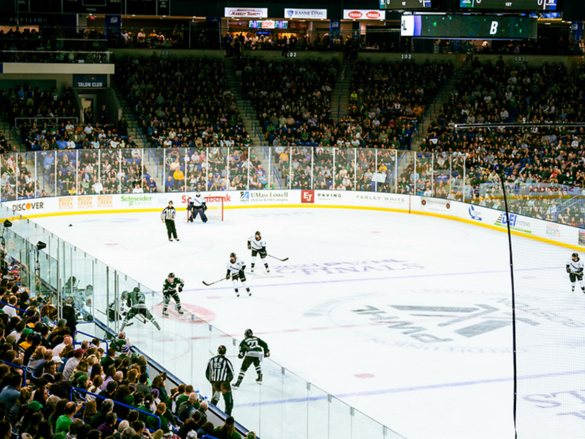 An above-ice level shot of Boston and Minnesota battling along the boards for the puck at the Tsongas Center.