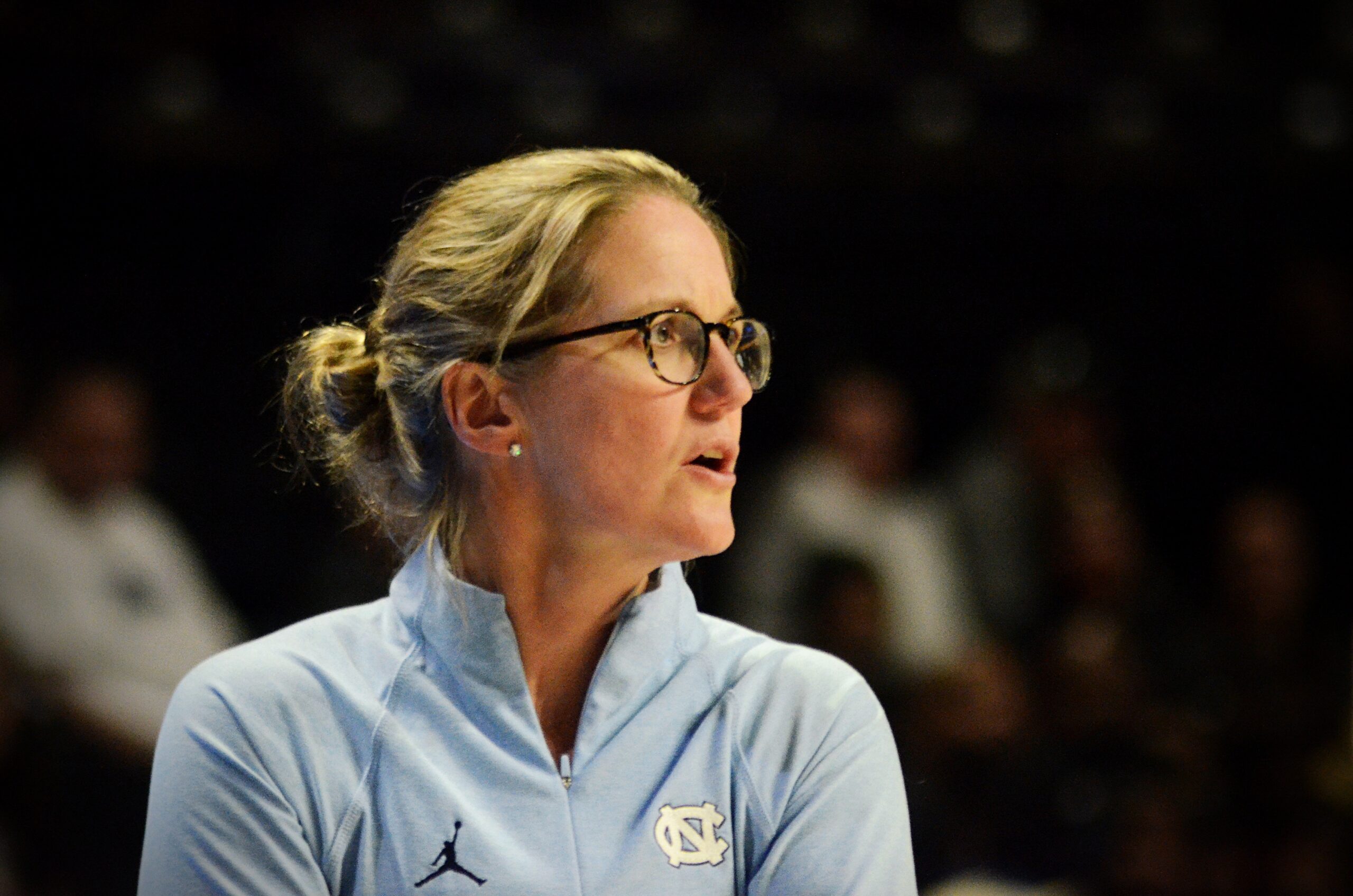 UNC head coach Courtney Banghart looks toward the court from the sidelines during a game.
