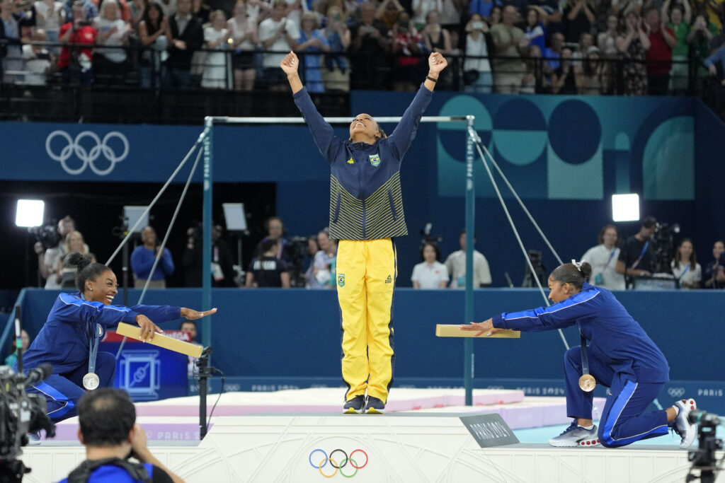Simone Biles, left, and Jordan Chiles, right, bow to Rebeca Andrade, center, as Andrade wins gold on floor exercise at the Paris Olympics.